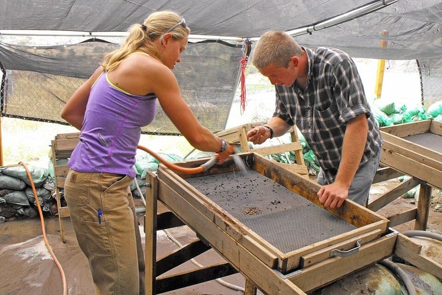 Archaeology field school students excavating a deep, stepped trench at the Cooper's Ferry site above the Salmon River in Idaho.